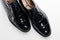 Diagonal Upper View of Pair of Formal Male Stylish Black Polished Oxford Leather Laced Shoes Placed Together Over White