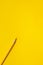 Diagonal yellow sharp wooden pencil on a bright yellow background, isolated, copy space, mock up