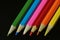 Diagonally lined up colored crayons on a black background