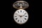 Dial of silver antique pocket watch with an open glass lid on isolated black background. Old mechanical clock. Round