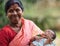 DIAMOND HARBOR, INDIA - APRIL 04, 2013 :Rural Indian woman with child in hands and in red sari smiles