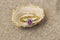 Diamond and ruby wedding ring jewellery on a shell on sand.