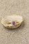 Diamond and ruby wedding ring jewellery on a shell on sand.