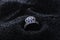 Diamond shape silver ring with blue gemstones on black sand