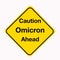 Diamond shaped yellow traffic warning sign with Caution Omicron Ahead as the message