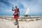 Diani Beach / Kenya - March 01 2020: Masai on the beach in Kenya, Diani Beach, watamu holding an arrow with a sail boat in the bac