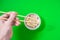 Dice in a white bowl with chopsticks on  green background