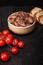 Diced raw game, beef meat in a bowl, on black background. Composition with red meat in cubes, cherry tomatoes and bread.