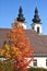 Die Stiftskirche in KremsmÃ¼nster mit einem herbstlichen Laubbaum Bezirk Kirchdorf, OberÃ¶sterreich - The Church of the Abbey in