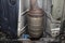 A diesel particulate filter in the exhaust system in a car on a lift in a car workshop, seen from below.