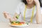 Diet in bored. Closeup broccoli unhappy beautiful asian young woman, girl on dieting, hand holding fork in salad plate, dislike or