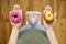 Diet concept. Dieting young woman measuring body weighing on weight scale, hold sweet donut and red apple, making choice between