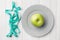 Diet concept. Green Apple on a plate and tape centimeter on a white table