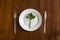 Diet concept. one green vegetable on an empty white plate with woman hands celery on wood table healthy