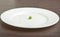 Diet concept. one pea on an empty white plate