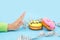 Diet or good health concept. hand rejecting unhealthy food like donuts or dessert isolated on blue background