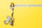 Diet and healthy eating concept with fork and measuring tape on yellow background. Top view of weightloss