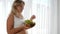 Diet during pregnancy, girl with big naked tummy holds wooden plate with fruits and eats grapes