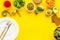 Diet program concept. Empty plate, measure tape and vegetables on yellow background top view copy space