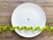 Diet. Suffering from anorexia. Cropped image pea on white plate, with fork and measuring