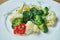 Diet and veggie snack - steamed vegetables broccoli, cauliflower and cherry tomatoes in a white plate on a wooden background