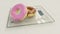 Diet versus calories abuse - delicious and tempting donuts with chocolate and pink icing and sprinkles on modern bathroom scale in