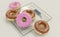 Diet versus calories abuse - delicious and tempting donuts with chocolate and pink icing and sprinkles on modern bathroom scale in