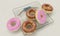 Diet versus calories abuse - delicious and tempting donuts with chocolate and pink icing and sprinkles on modern bathroom scale in