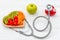 Diet and weight loss for healthy care with medical stethoscope, vegetable fruit and healthy food with red heart on the old white w