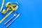 Diet, weight loss, slimming concept. Fork and knife with wound measuring tape on blue background top view space for text