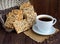 Dietary crunchy cracker with cereals (sunflower seeds, flax and sesame) and a cup of tea on a dark