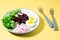 A dietary dish made from vegetables. Beet tartare, radish, frieze salad and boiled egg on a plate and a fork