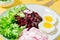 A dietary dish made from vegetables. Beet tartare, radish, frieze salad and boiled egg on a plate on a yellow background