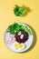 A dietary dish made from vegetables. Beet tartare, radish, frieze salad and boiled egg on a plate on a yellow background