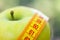 Dieting concept. Green apple with measuring tape. Green apples measured the meter, sports apple