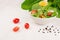 Dieting raw healthy food - fresh green salad with tomatoes, pepper and olive oil on soft white wood board, closeup, copy space.