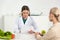 Dietitian in white coat holding paper and patient