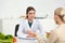 Dietitian in white coat looking at patient at table