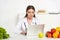 Dietitian in white coat using laptop at workplace with fruits and vegetables