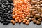 Different assorted lentils mix with red, brown and black beluga lentils on dark stone background macro
