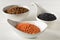 Different assorted lentils mix with red, brown and black beluga lentils in white bowls on white wooden table background