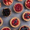 Different berry tarts on grey table, flat lay. Delicious pastries