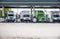 Different big rigs semi trucks with semi trailers standing on the fuel station for refueling for continue the cargo delivery route