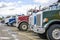 Different big rigs semi trucks tractors standing in row on the warehouse parking lot waiting for next loads for delivery