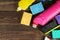 Different bottles with cleaning products and detergents and washcloths in a blue bucket on a brown wooden table. top view