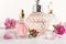 Different bottles of perfume and flowers on light background