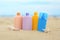 Different bottles with sun protection creams and seashells on beach near sea