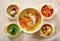 Different bowls with meat, poultry, vegetable and legume soups.