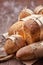 Different bread on the wooden table, flour, paper bags, rope. Brown background.