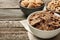 Different breakfast cereals in bowls on wooden table, closeup. Space for text